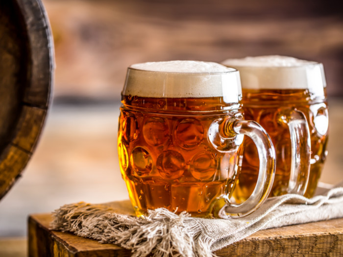 Two mugs full of ale on a cloth atop a wooden box