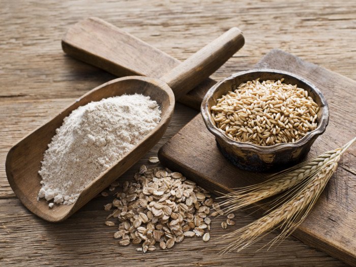 A spoonful of flour, wheat, and oats on a table