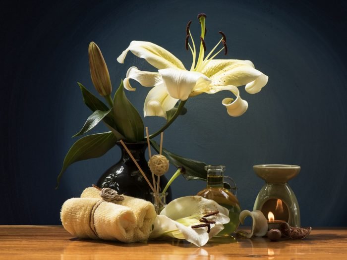 A bottle of essential oil for good sleep with white flowers and napkins on a wooden table