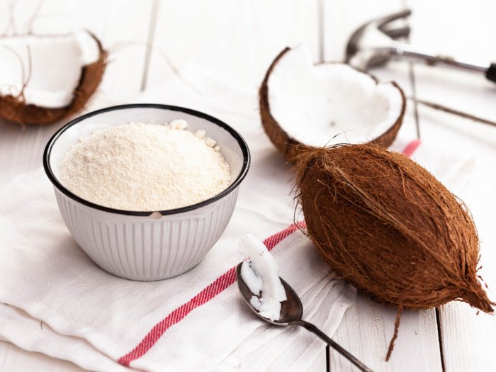 A bowl of coconut flour and coconuts kept aside on a white napkin