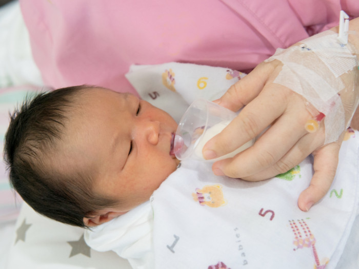 a newborn being fed milk through a cup