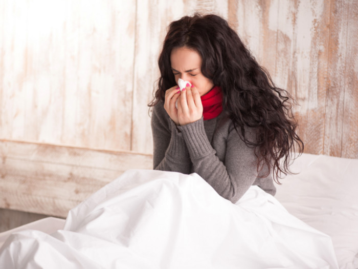 A sick woman blowing her nose.