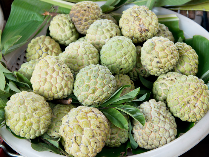 A bunch of custard apples on banana leaves on a large plate