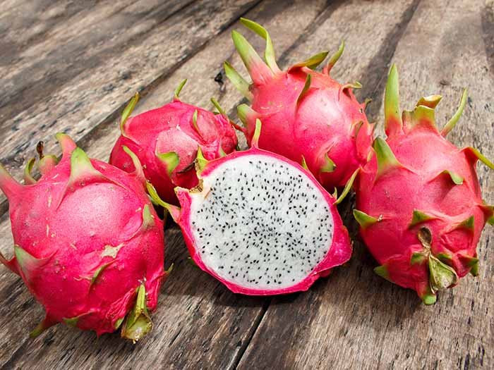 Freshly cut and uncut dragon fruits on a wooden table