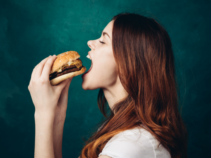 A girl holding a burger and about to eat it