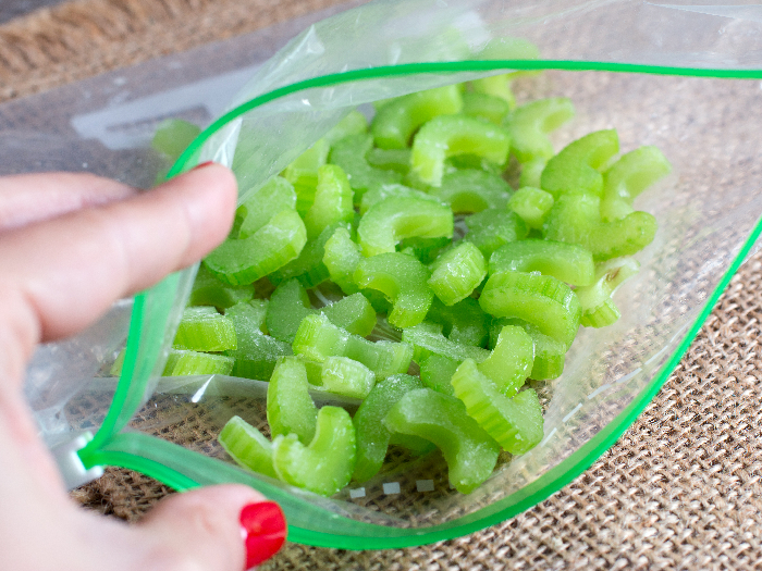 Frozen pieces of celery in a bag on a wooden board