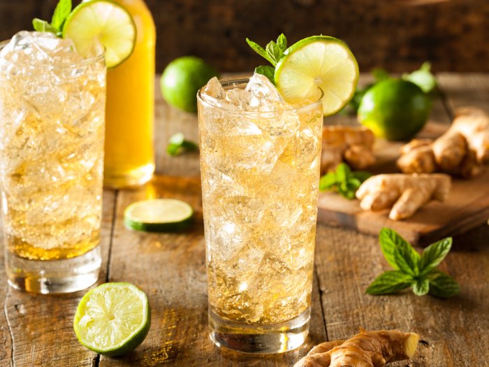 Tall glasses of ginger beer with lime, mint, and ice cubes