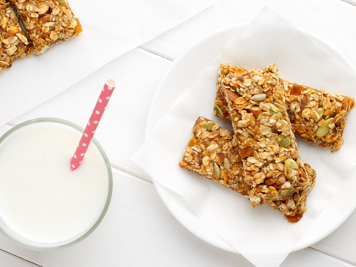 Healthy breakfast with granola bars and milk on white wooden table