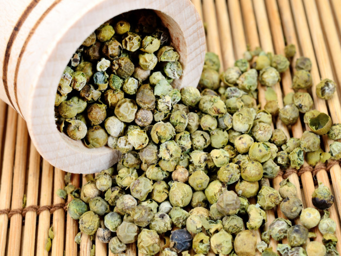 Green peppercorns spilling from a bottle