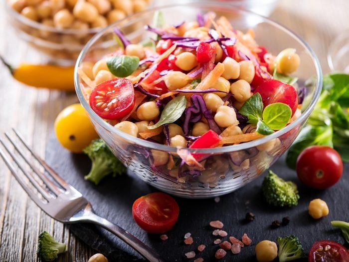 A bowl filled with chickpeas salad and cherry tomatoes beside