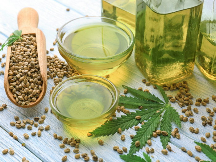 A close-up image of hemp raw seeds and oil on a wooden table