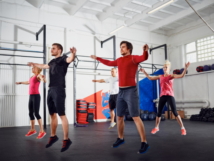 People performing jumping jacks in a gym