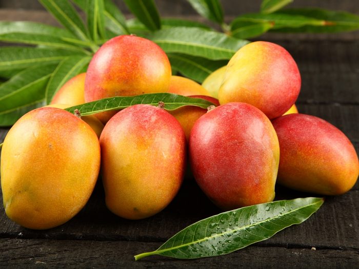 Mangoes with a reddish-yellow skin on a wooden counter