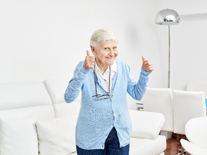 An older woman holds the thumbs up full of happiness and excitement