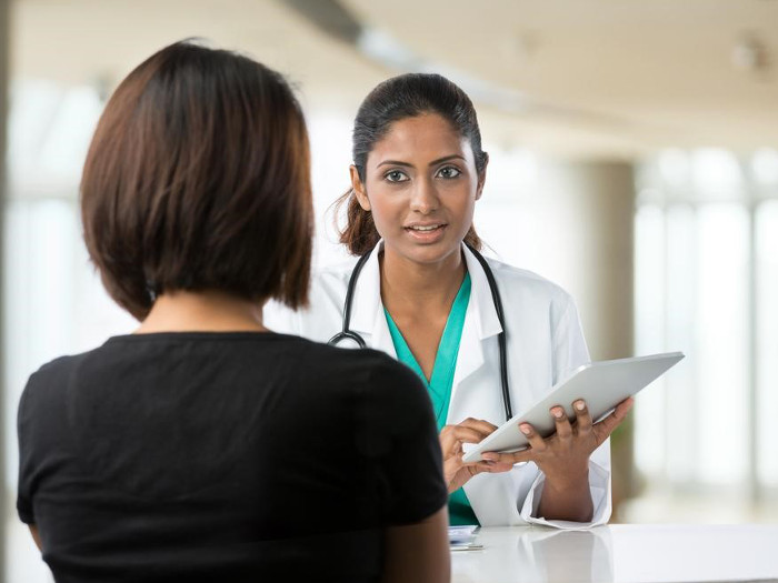 A doctor with a stethoscope and a clipboard, talking to a patient