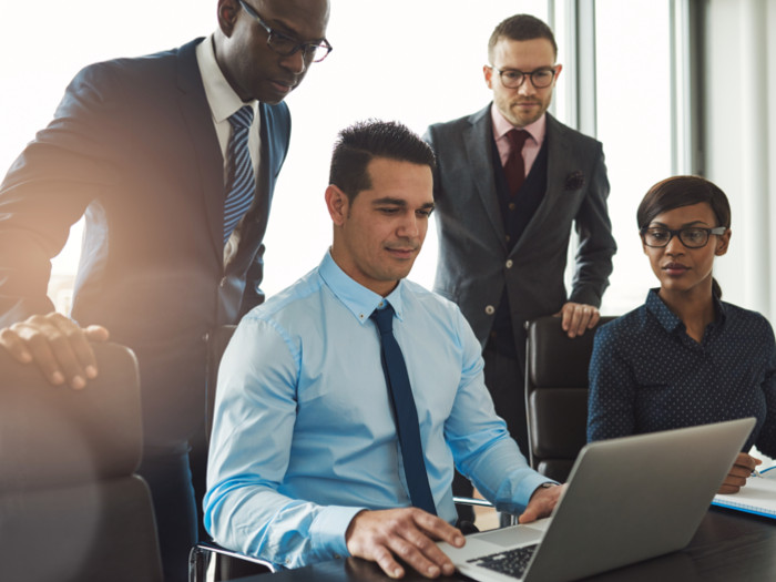 Four people in an office looking into a laptop
