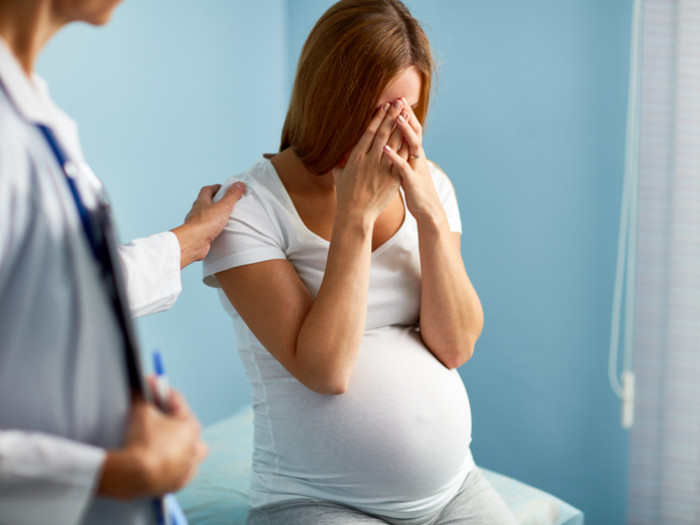A pregnant woman with her hands over her face