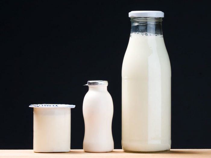 Bottles of probiotic milk on a wooden table with a dark background