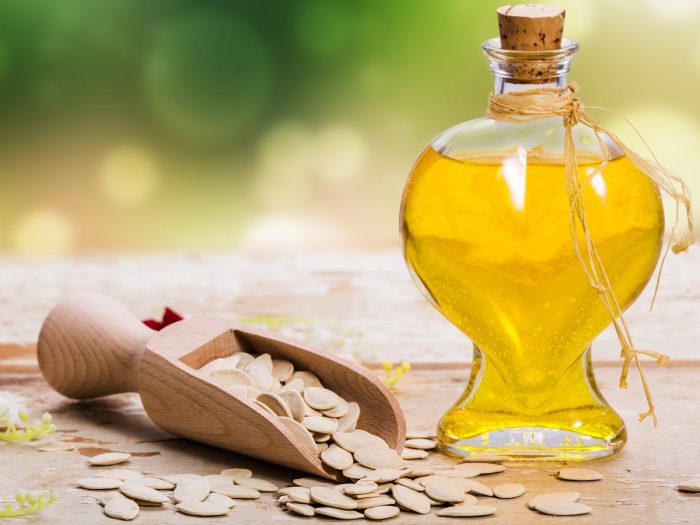Pumpkin seed oil in a bottle surrounded by pumpkin seeds