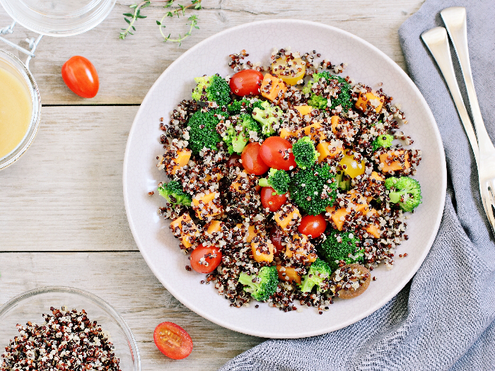 Quinoa salad with broccoli, sweet potatoes and tomatoes on a rustic wooden table. Three-color quinoa salad