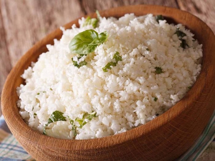 Cauliflower rice or grated cauliflower with basil leaves, in a bowl