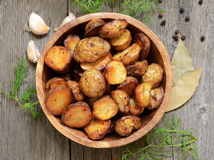 Roasted potato in bowl on wooden table - Image