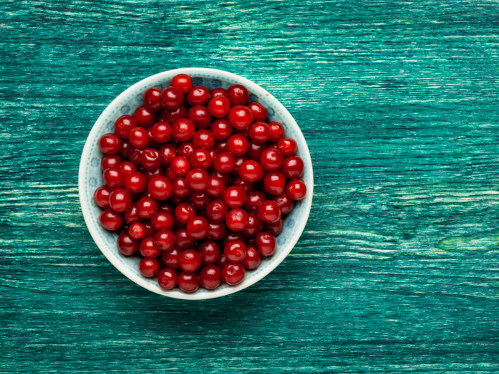 Bowl of sour cherries in a white bowl, placed on a blue wood surface