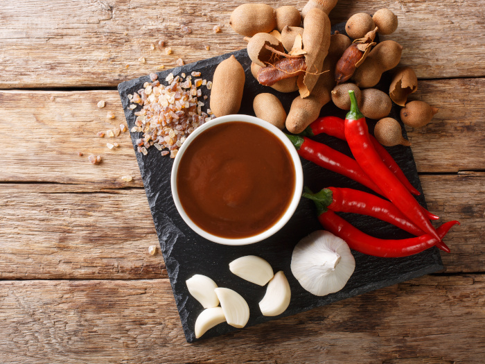 Sweet and sour spicy tamarind chutney with ingredients close-up on a wooden table